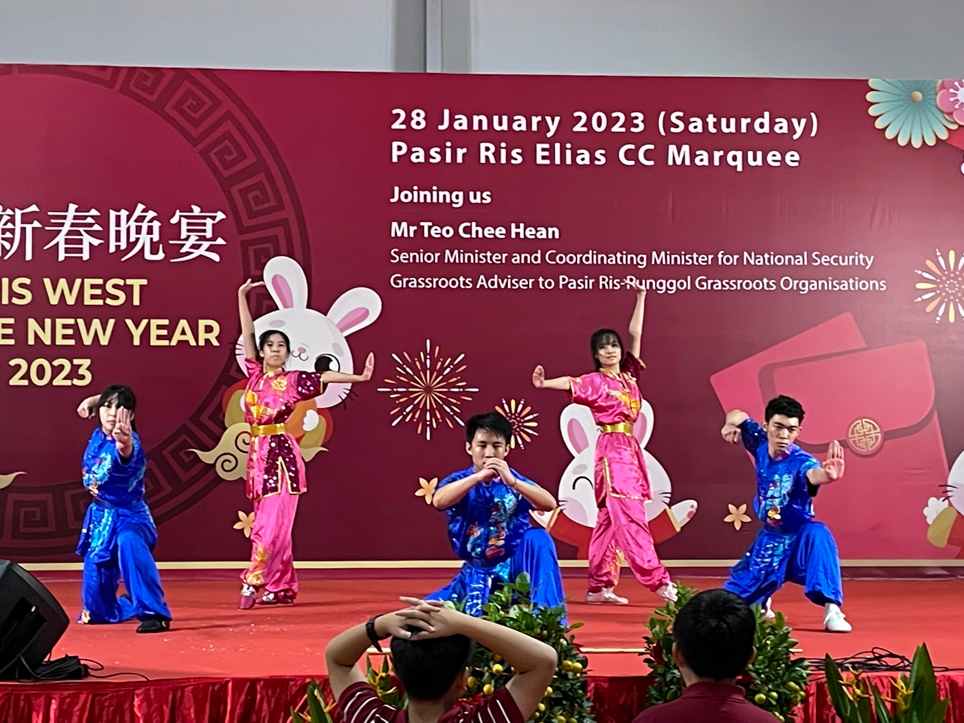 Five TMJC wushu students in bright pink and blue costumes perform a coordinated routine on stage at the Pasir Ris West Chinese New Year Dinner on 28 January 2023.